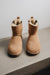 Pair of tan sheepskin boots on a light grey stone surface with a neutral background