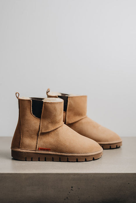 Profile view of a pair of tan coloured sheepskin boots with 'Heatons' branding and a chunky sole.