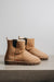 Profile view of a pair of tan coloured sheepskin boots with 'Heatons' branding and a chunky sole.