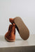 Rust coloured sheepskin slipper boot with rubber sole showing on a light grey background