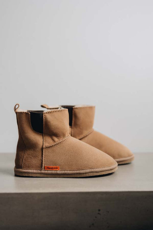 Side view of the Sheepskin, Chelsea boot style, slipper. A classic sheepskin boot with elastic panels on both sides and an orange cork Heatons label.