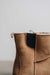 Close-up of a tan sheepskin Chelsea style boot with elastic side panels against a plain background