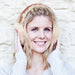 Natural Sheepskin Earmuffs, worn by a Blonde Female Model smiling.