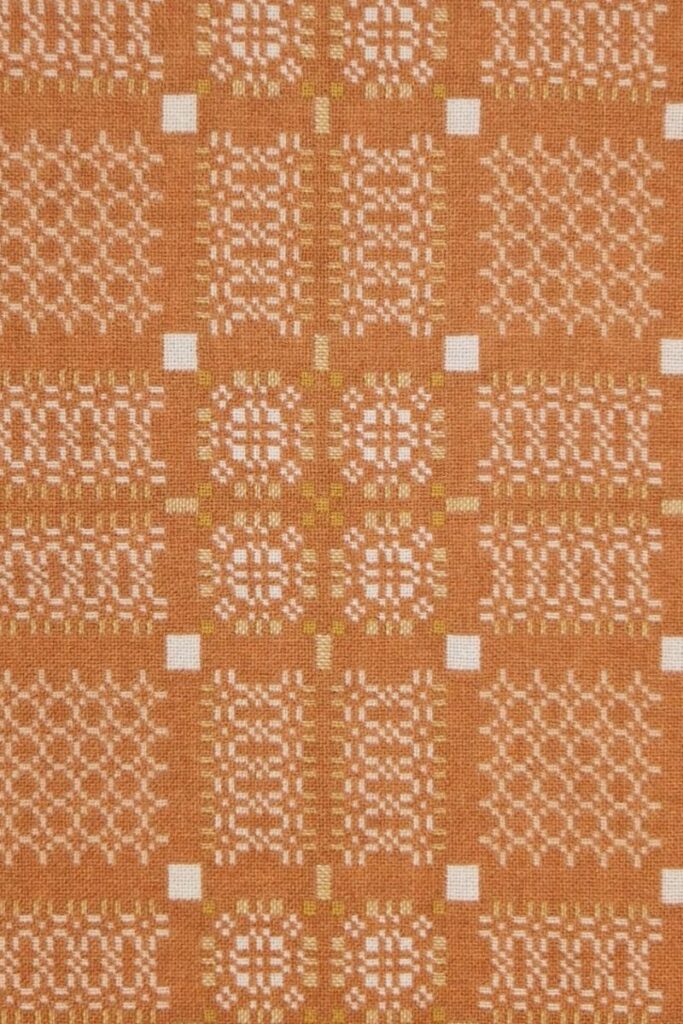 Melin Tregwynt woven wool square cushion with a orange and white woven Knot Garden pattern