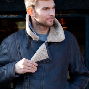 Men's Sheepskin and Leather Blenheim Chocolate Aviator Jacket. Male model wears jacket, undoing the front zip.