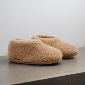 Side view of a camel coloured curly merino sheepskin boot slipper.