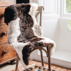British Jacob rug in Natural white and brown spots draped over a wooden chair