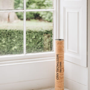 A Yoga mat of natural latex rubber, topped with soft and sustainable Portuguese cork standing next to window - space saving