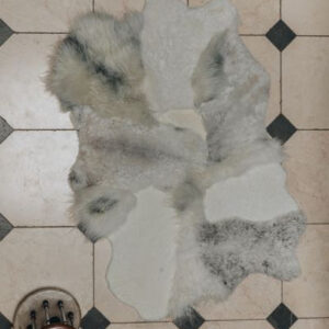 Multilayer designer sheepskin rug in natural melange tones and mixed lengths on a tiled floor 