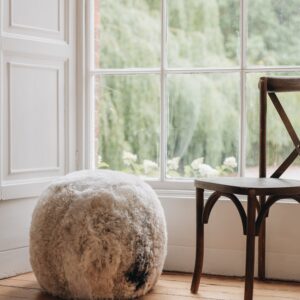 an Icelandic sheepskin footstool/pouffe in a melange colouration, grey and brown mixed tones in a natural pattern