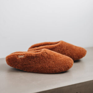 Side view of Curly merino sheepskin slip on slipper with curls on the outside and inside in a rich, warm rust colour.