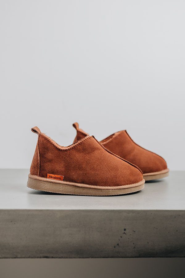 Henry rust men’s sheepskin slippers placed side-by-side on stone surface