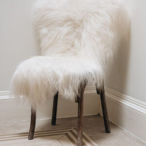 Icelandic Long Wool Sheepskin Rug in White, draped over wooden chair.