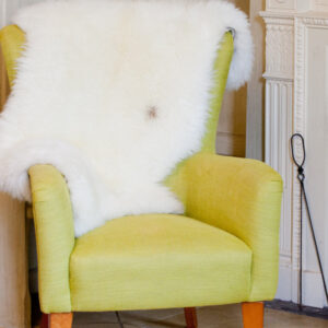 Fireside  appeal - All Natural British Sheepskin Rugs - Natural white nestled in the back of a high backed  chair by the fire