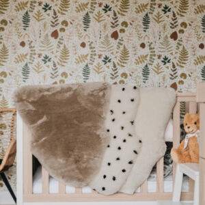 Sheepskin Nursing rugs in Toast, Spotted and Milk draped over a cot in a nursery