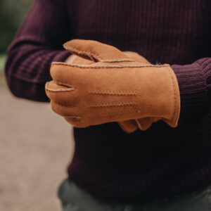 man wearing tan sheepskin gloves